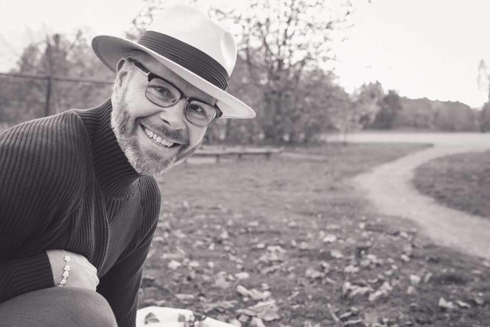Andreas-Dahlbäck_960x640 En leende man med skägg, glasögon och hatt utomhus